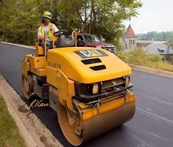 A yellow roller is sitting on top of a dirt field.