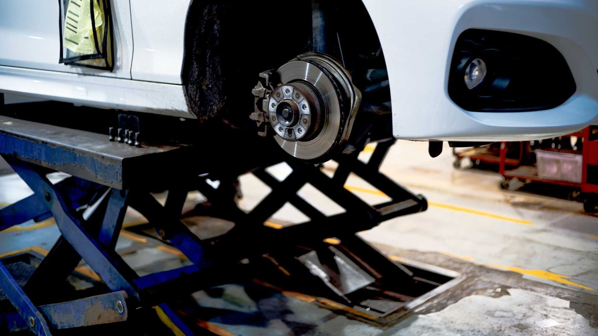 A car is sitting on a lift in a garage.