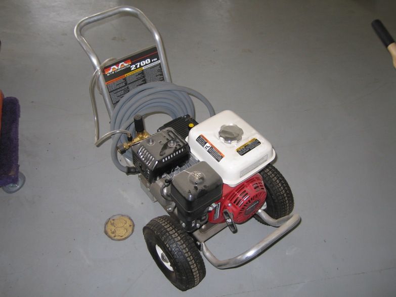 A gas powered pressure washer with a hose attached to it