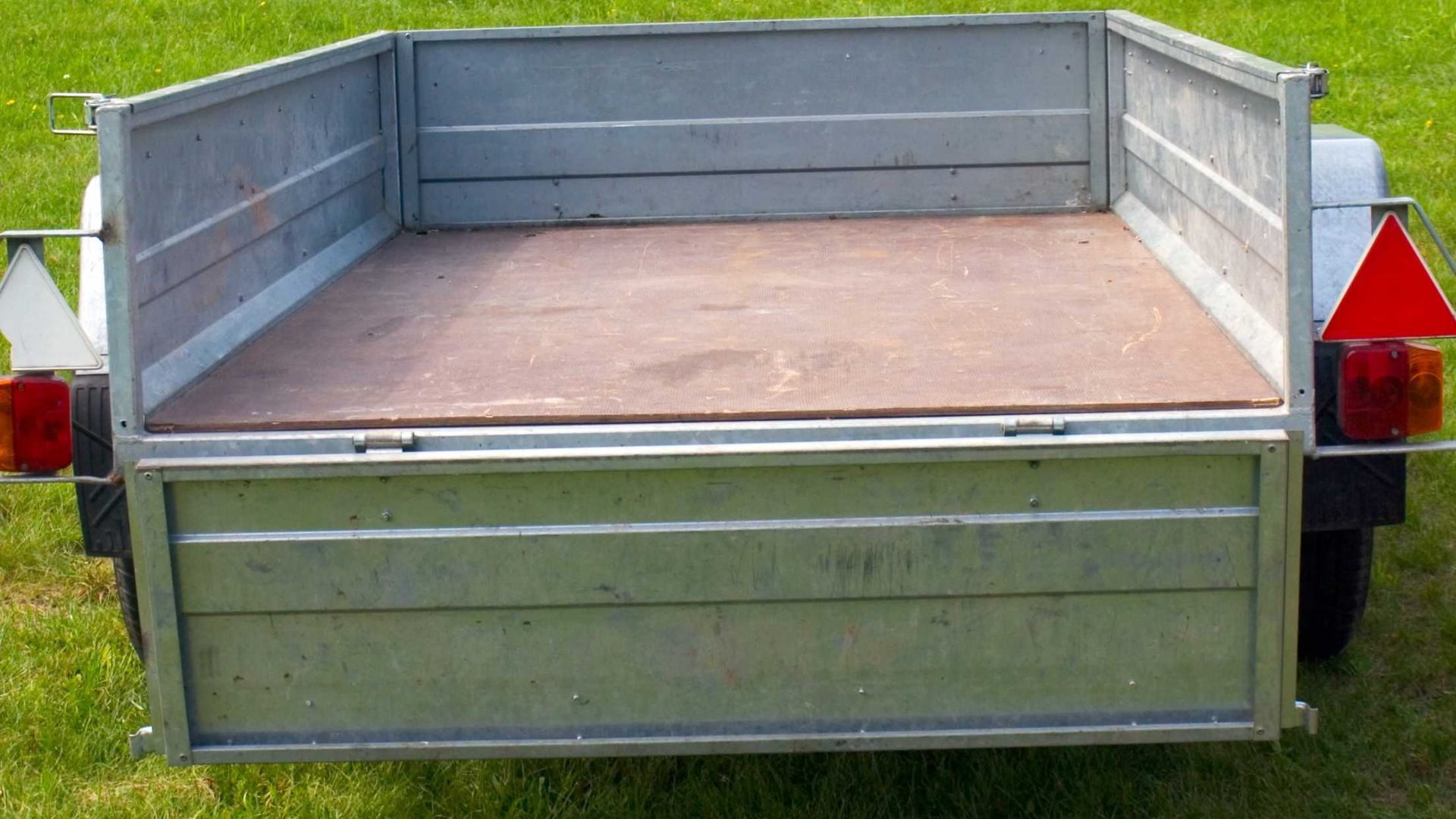 A trailer with a wooden floor is parked in the grass