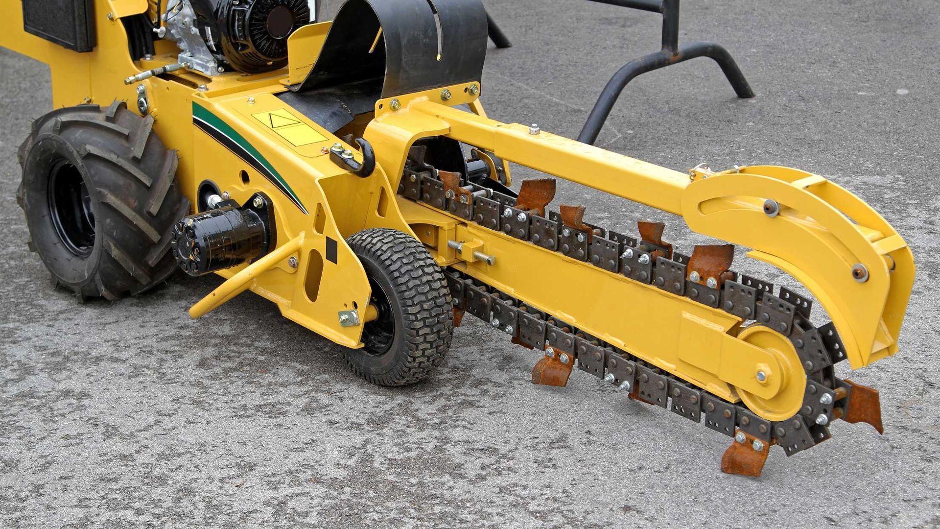 A yellow tractor with a chainsaw attached to it