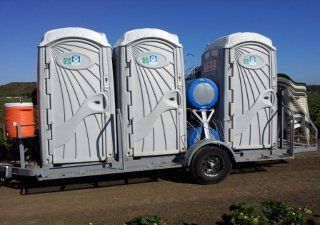 A trailer with three portable toilets on it.