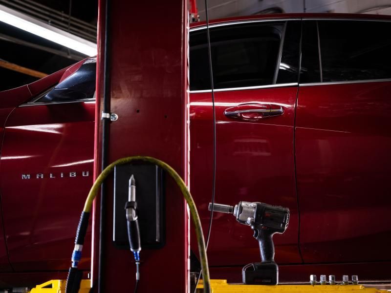Red vehicle on a lift with tire inflator and tools in the foreground at Musser Automotive.