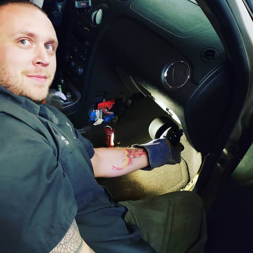 Owner Jason Musser explaining details under the dash of a vehicle at Musser Automotive.
