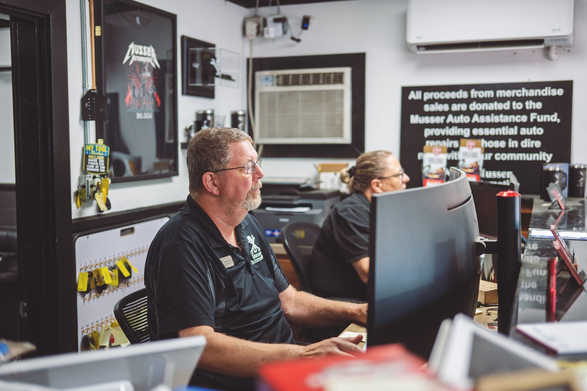 Two people working at computers in an office setting. | Musser Automotive