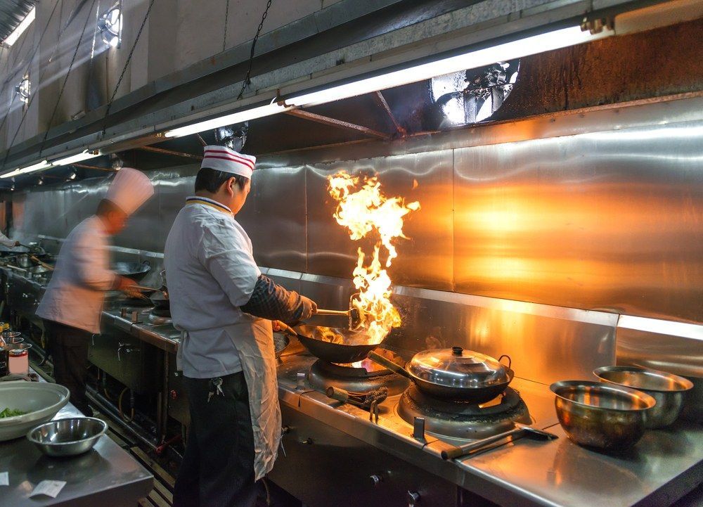 A Chef is Cooking Food on a Stove in a Kitchen — Kowin Restaurant in Forster, NSW