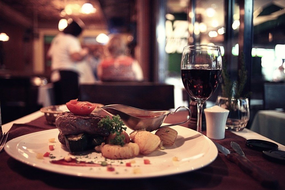 A Plate of Food and a Glass of Wine on a Table in a Restaurant — Kowin Restaurant in Harrington, NSW