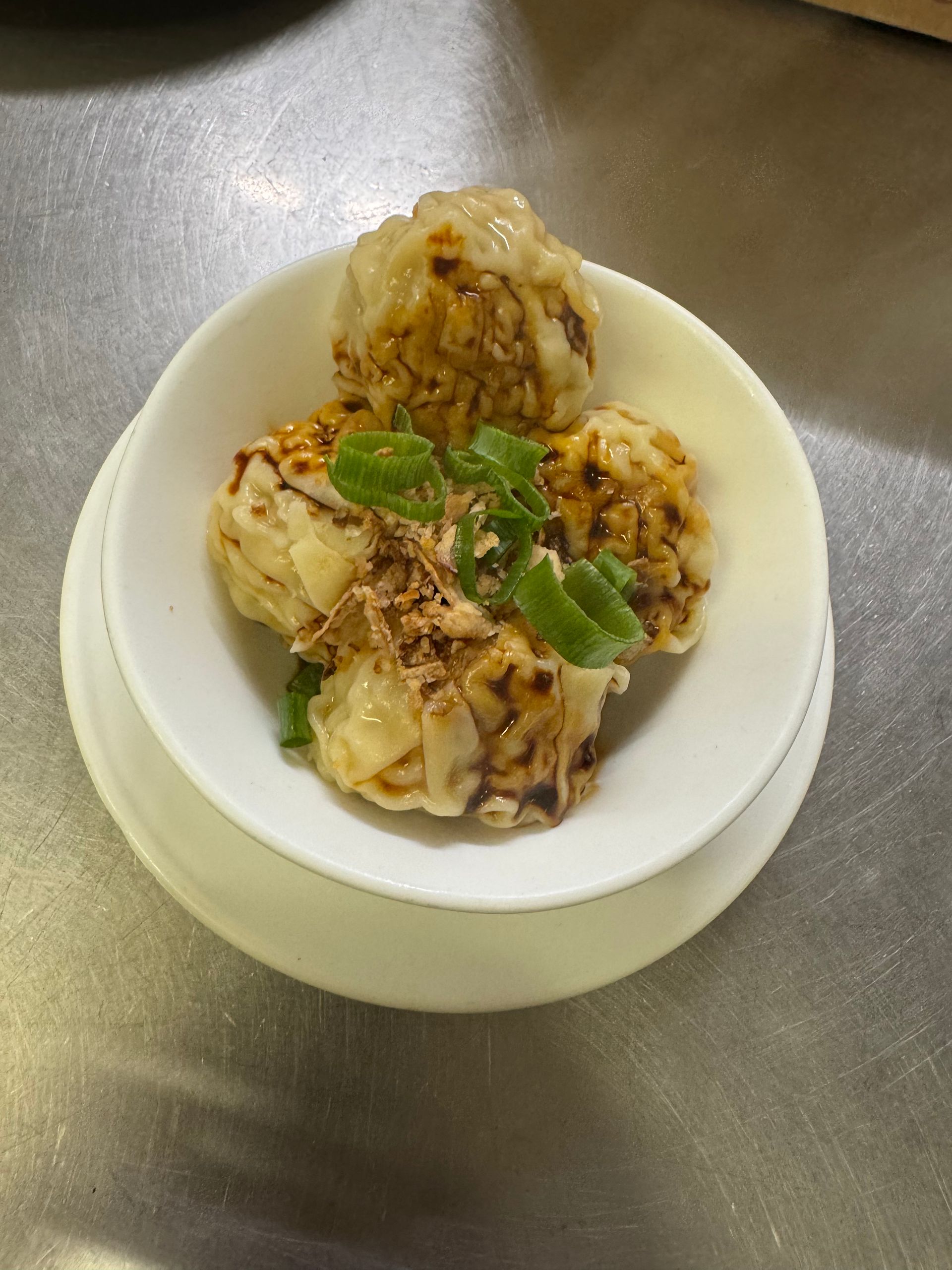 Dim sum in a white bowl, drizzled with sauce and garnished with green onions. — Kowin Restaurant in Old Bar, NSW