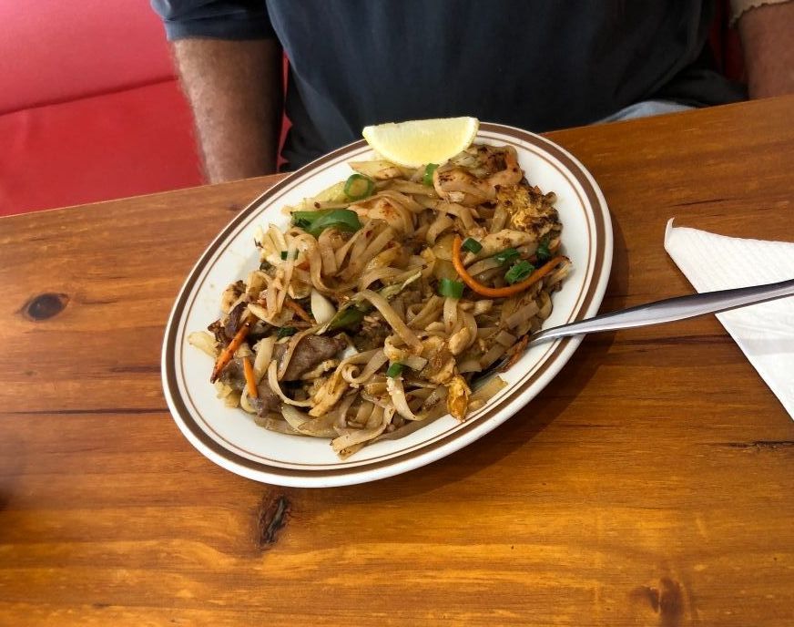 A Plate of Food With a Spoon and Napkin on a Wooden Table — Kowin Restaurant in Taree, NSW