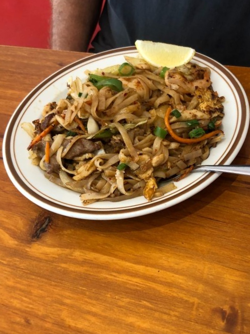 A Plate of Food With a Spoon and Napkin on a Wooden Table — Kowin Restaurant in Old Bar, NSW
