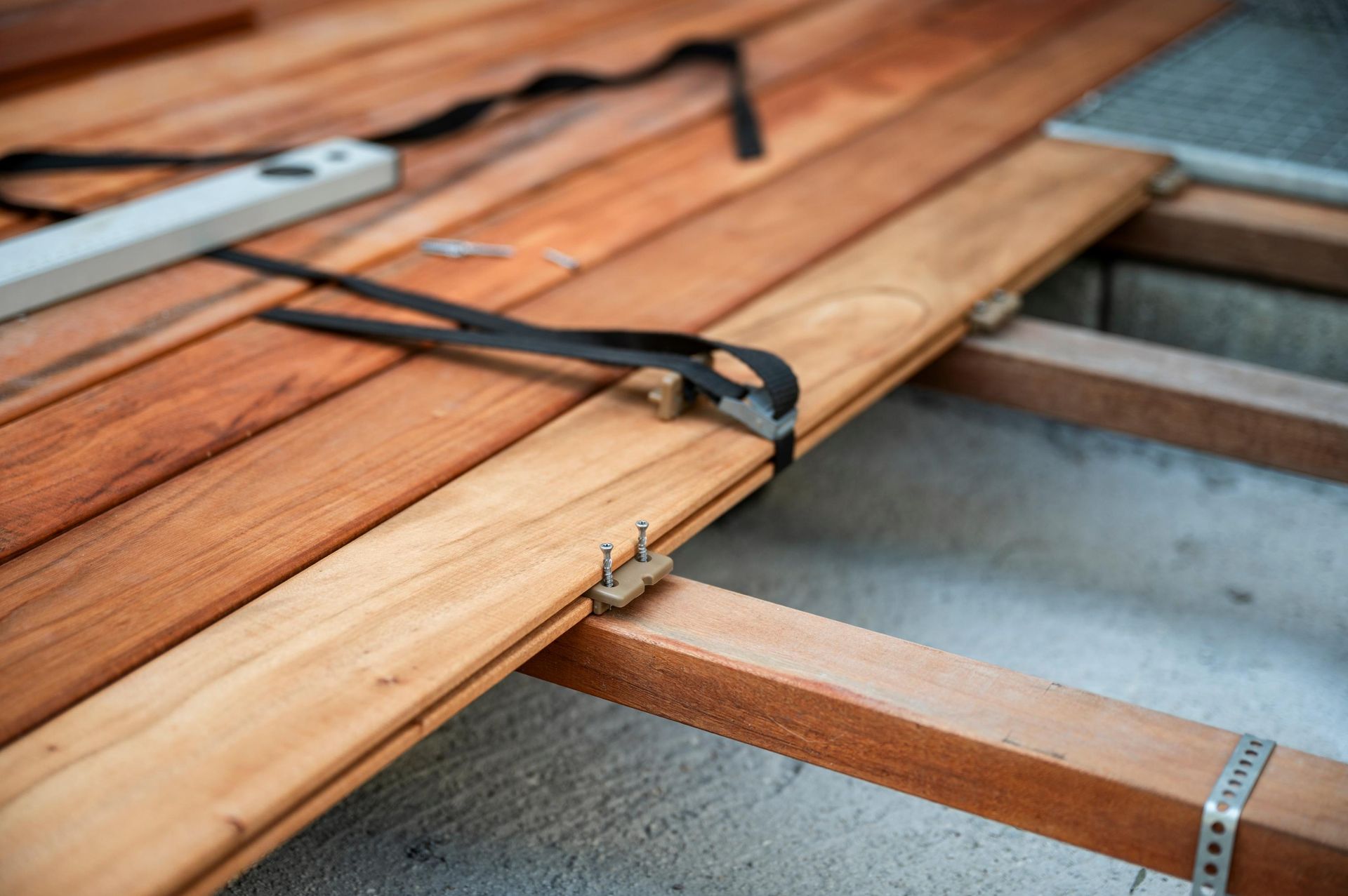 Decking boards being installed; boards are clamped and screwed in place over supporting frame.