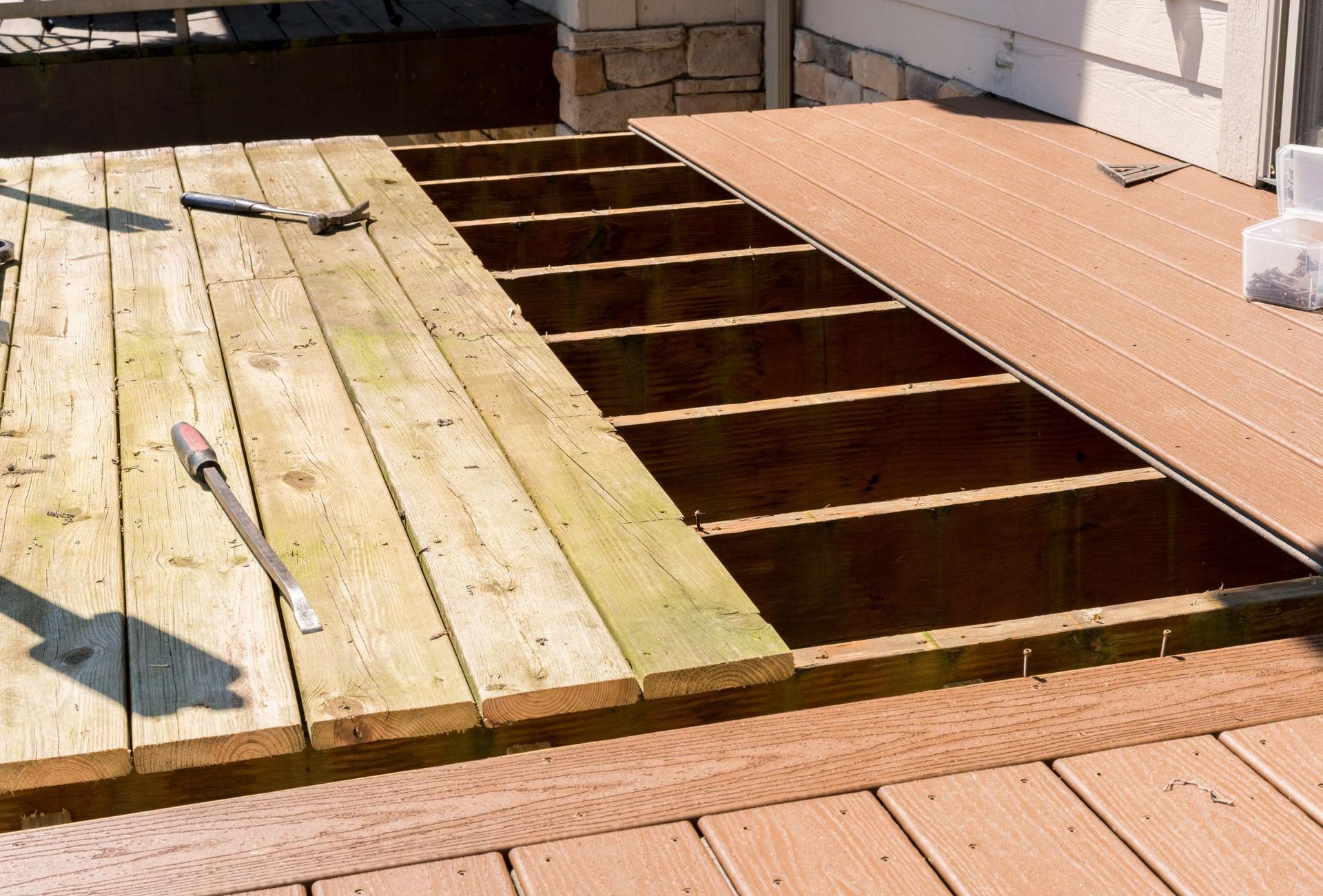 Deck repair: partially disassembled wooden deck with exposed joists, boards removed and awaiting replacement.