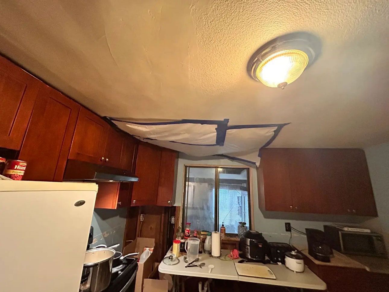 A kitchen with a ceiling that has been damaged by a fire