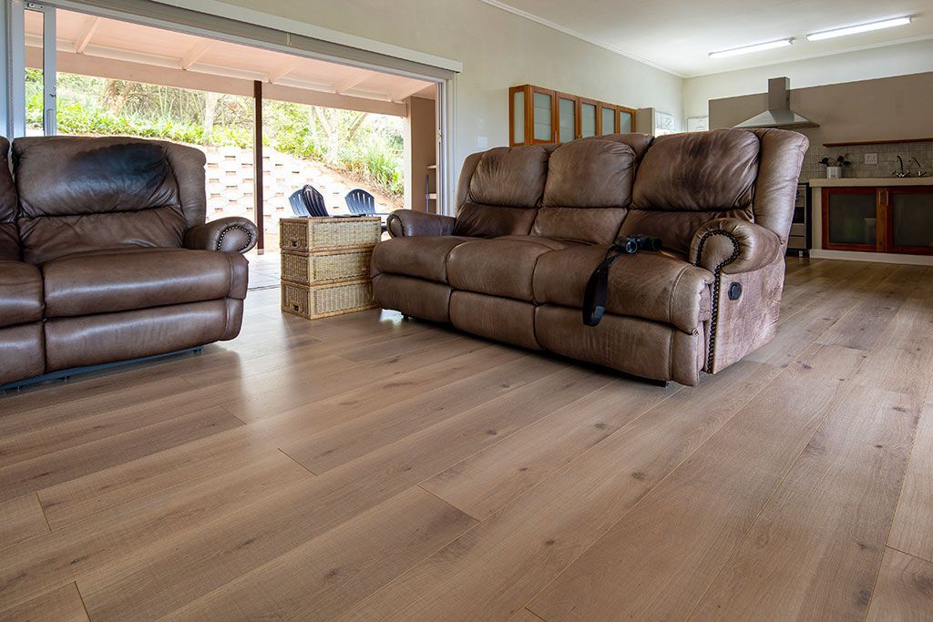 A living room with a couch and two chairs on a wooden floor.