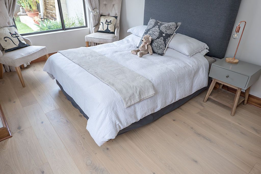 A bedroom with a bed , nightstand , chair and window.
