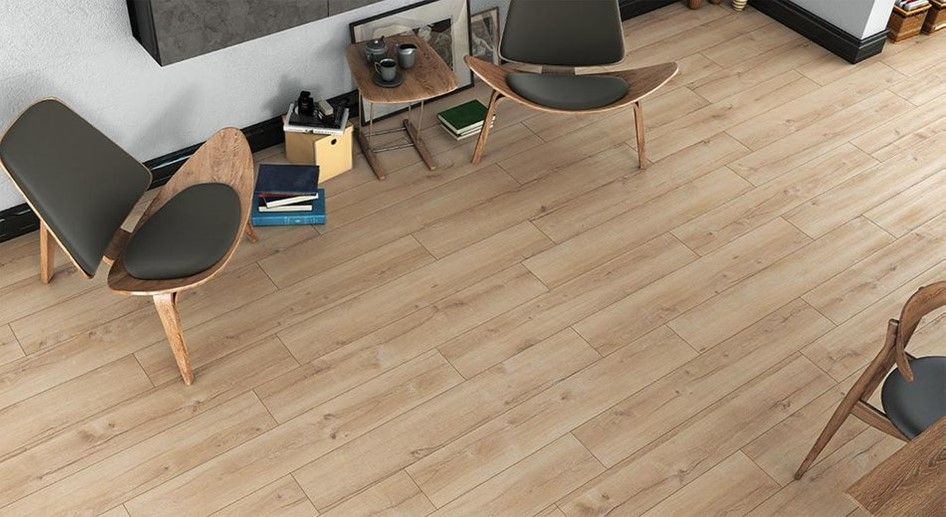 A living room with a wooden floor , two chairs , a table and a fireplace.