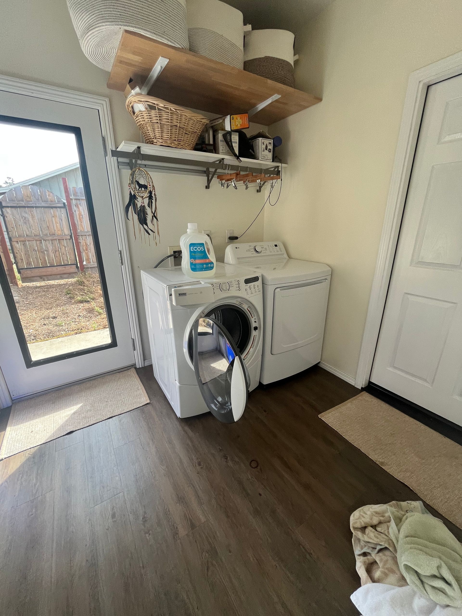 Laundry room with a washer, dryer, shelves, and a door to the outside.