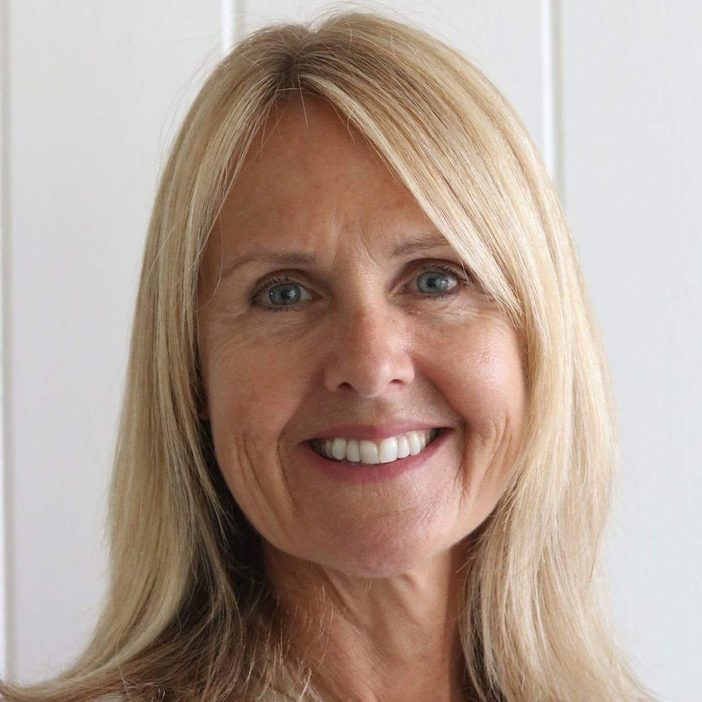 Woman with blonde hair smiles at the camera against a white background.