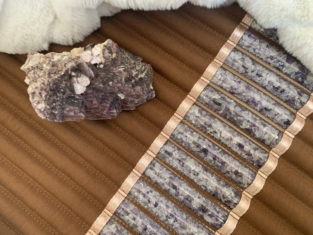 A brown, textured surface with a chunk of purple-grey rock, and decorative patterned trim.