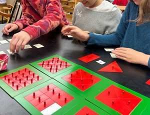 Children explore geometric equivalence using Montessori fraction and area materials.
