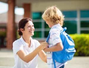 Adult warmly greets child after school, supporting calm transition and connection