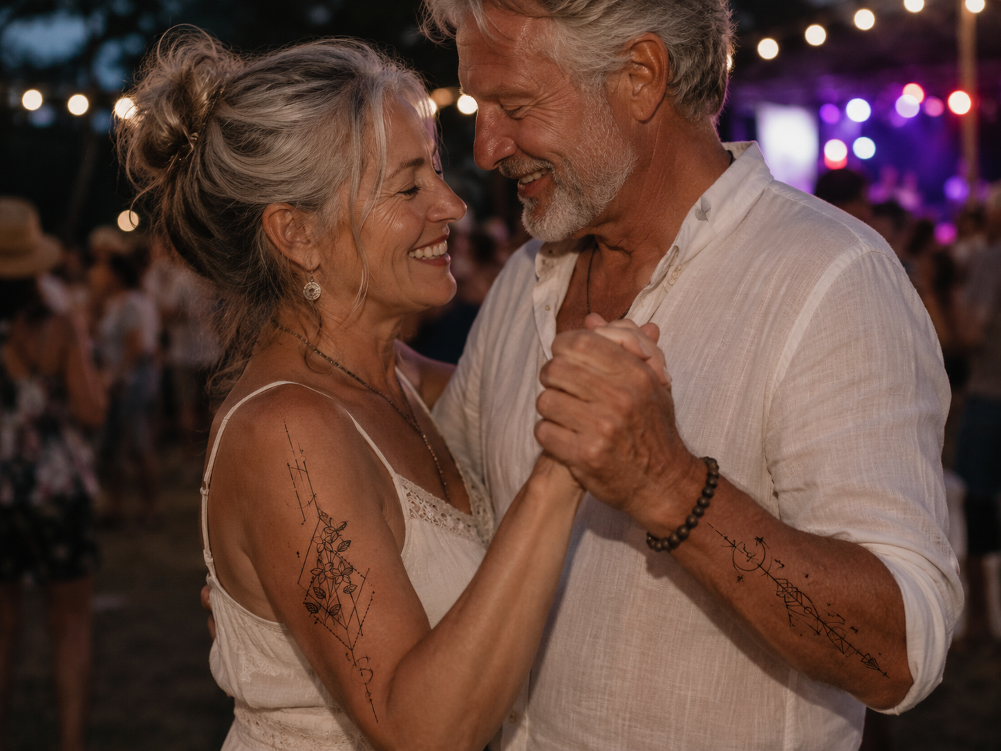 Couple dancing closely and smiling at an outdoor evening party with colorful lights