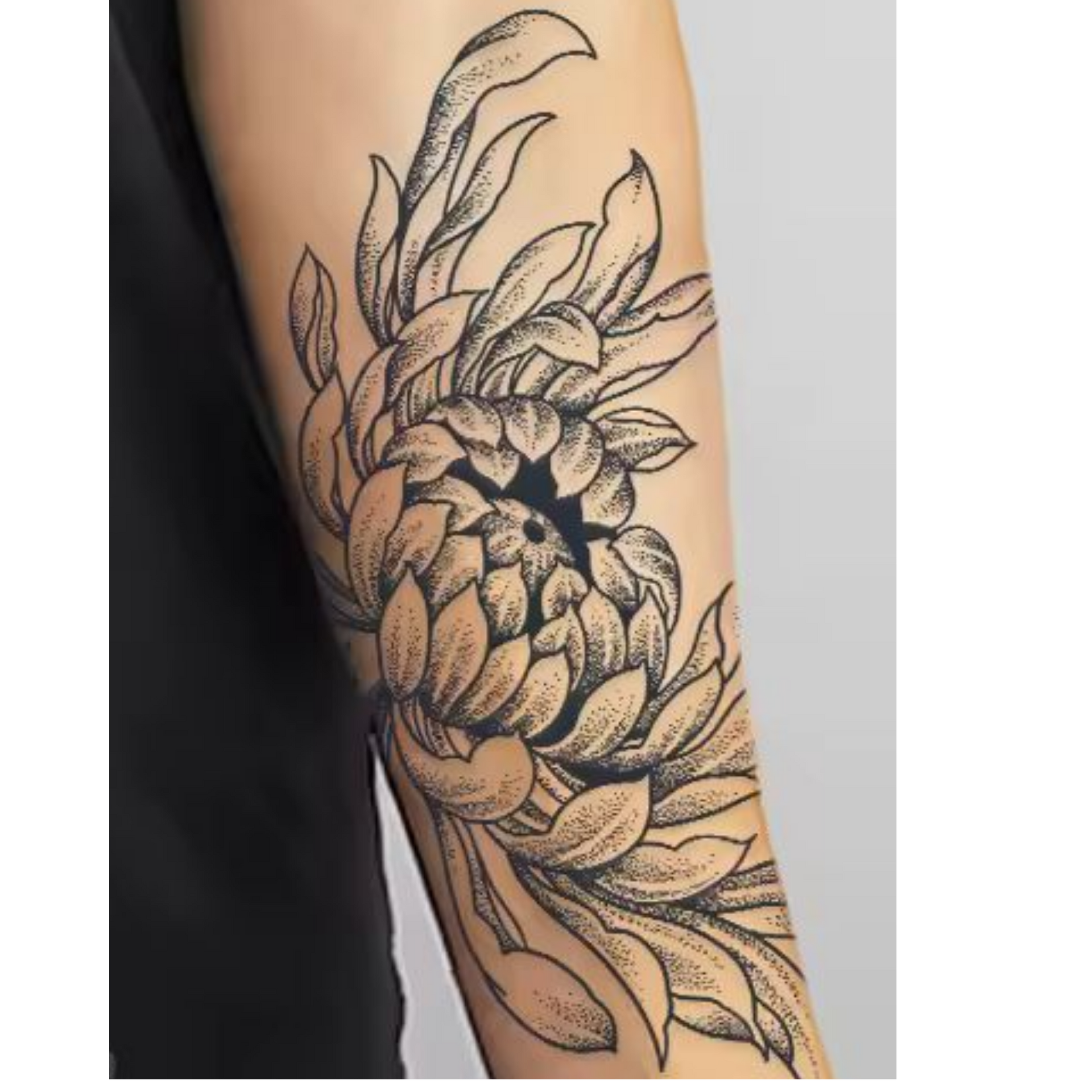 Black line-art floral tattoo on a person’s forearm, featuring a large chrysanthemum-like flower and leaves