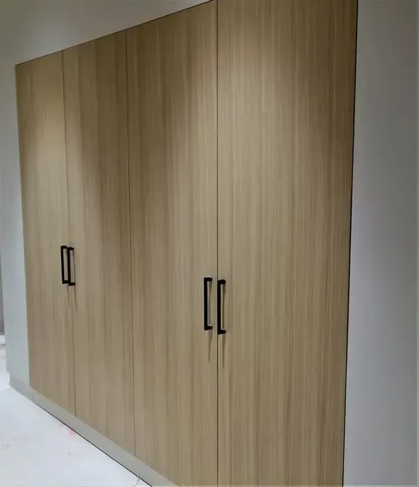 A row of wooden cabinets with black handles in a room.