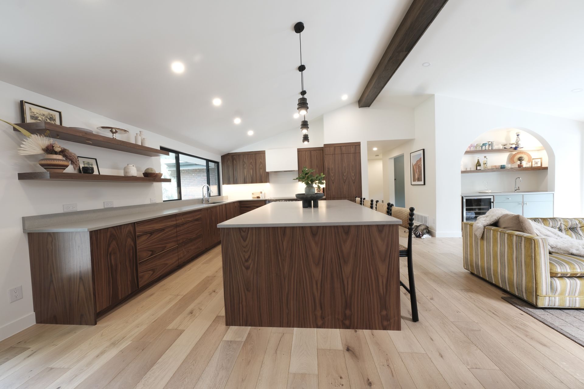 Bright modern kitchen and dining area with wood cabinetry, island, and open shelving