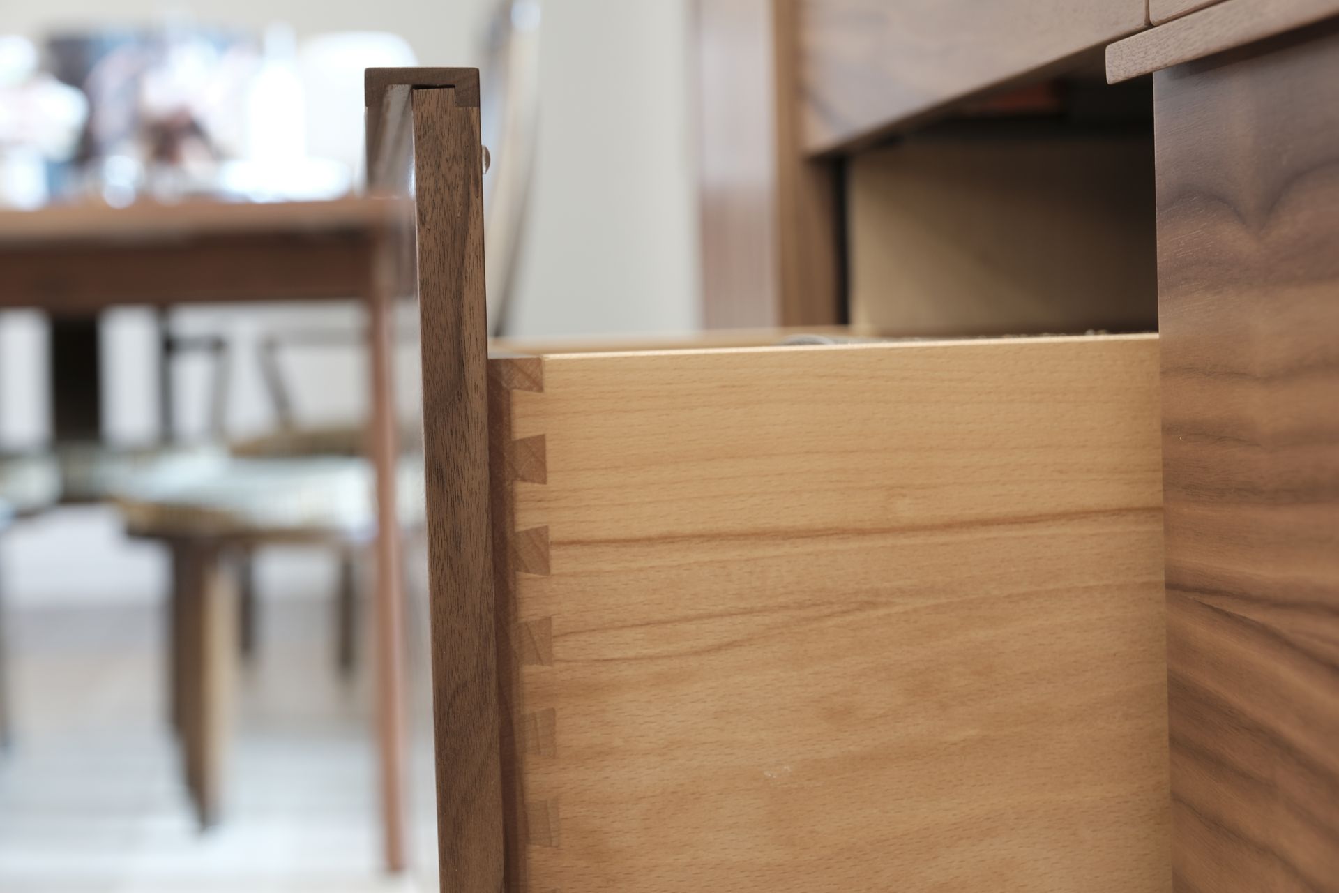 Close-up of a wooden drawer partially pulled out beside a table leg.
