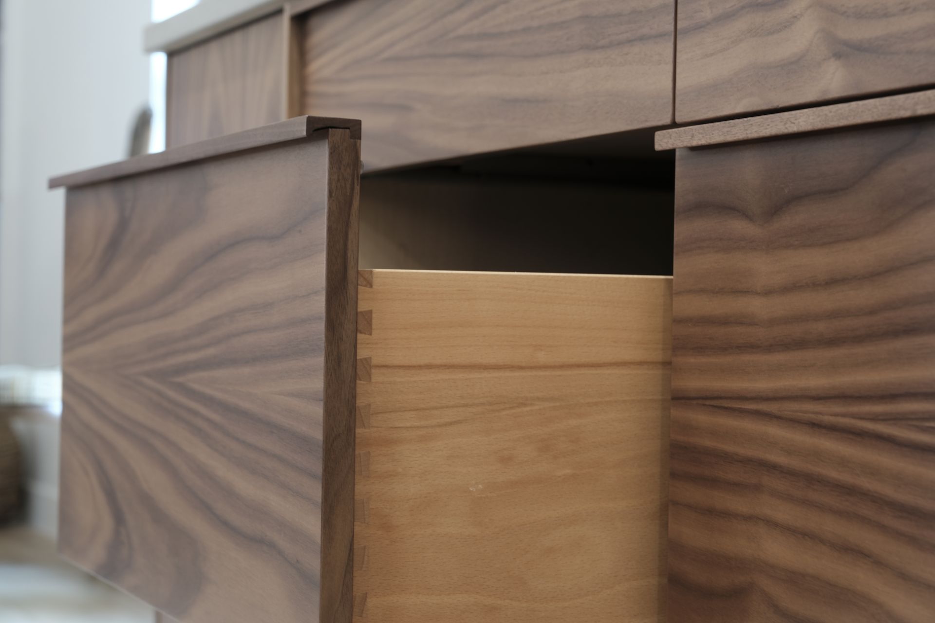 Wooden dresser drawer partially open, showing the light wood interior and dark wood exterior.