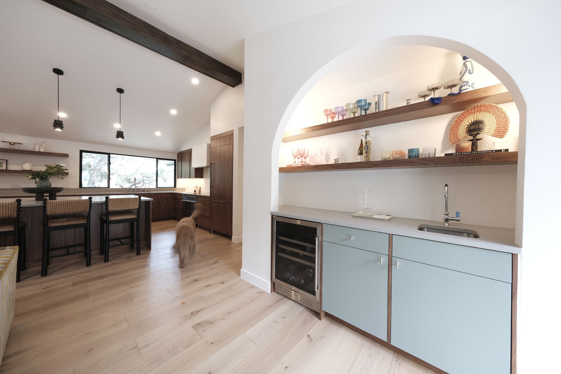 Bright modern kitchen and dining area with light wood floors, island seating, and built-in shelving
