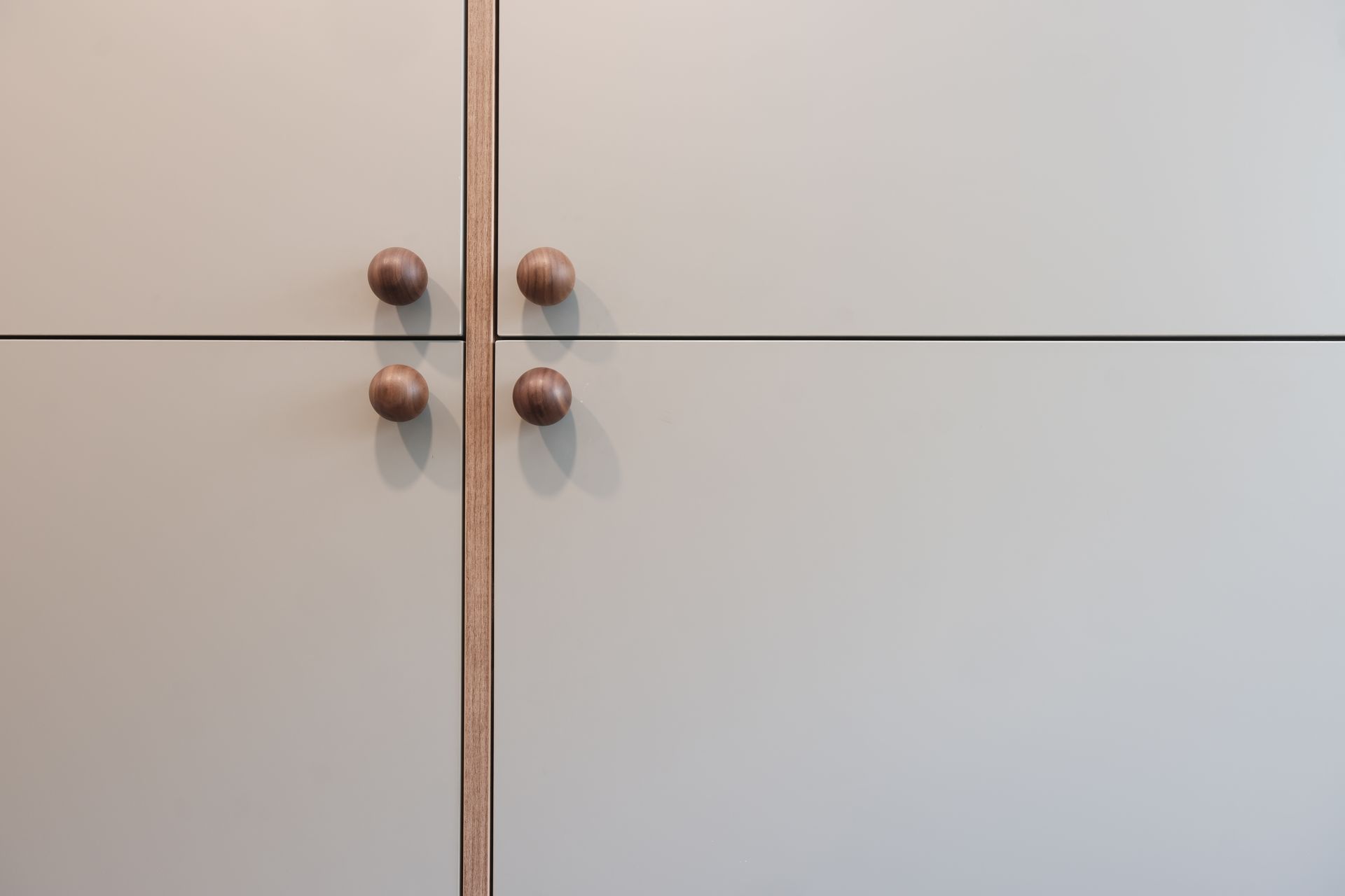 White cabinet doors with four round wooden knobs and a vertical wood trim line