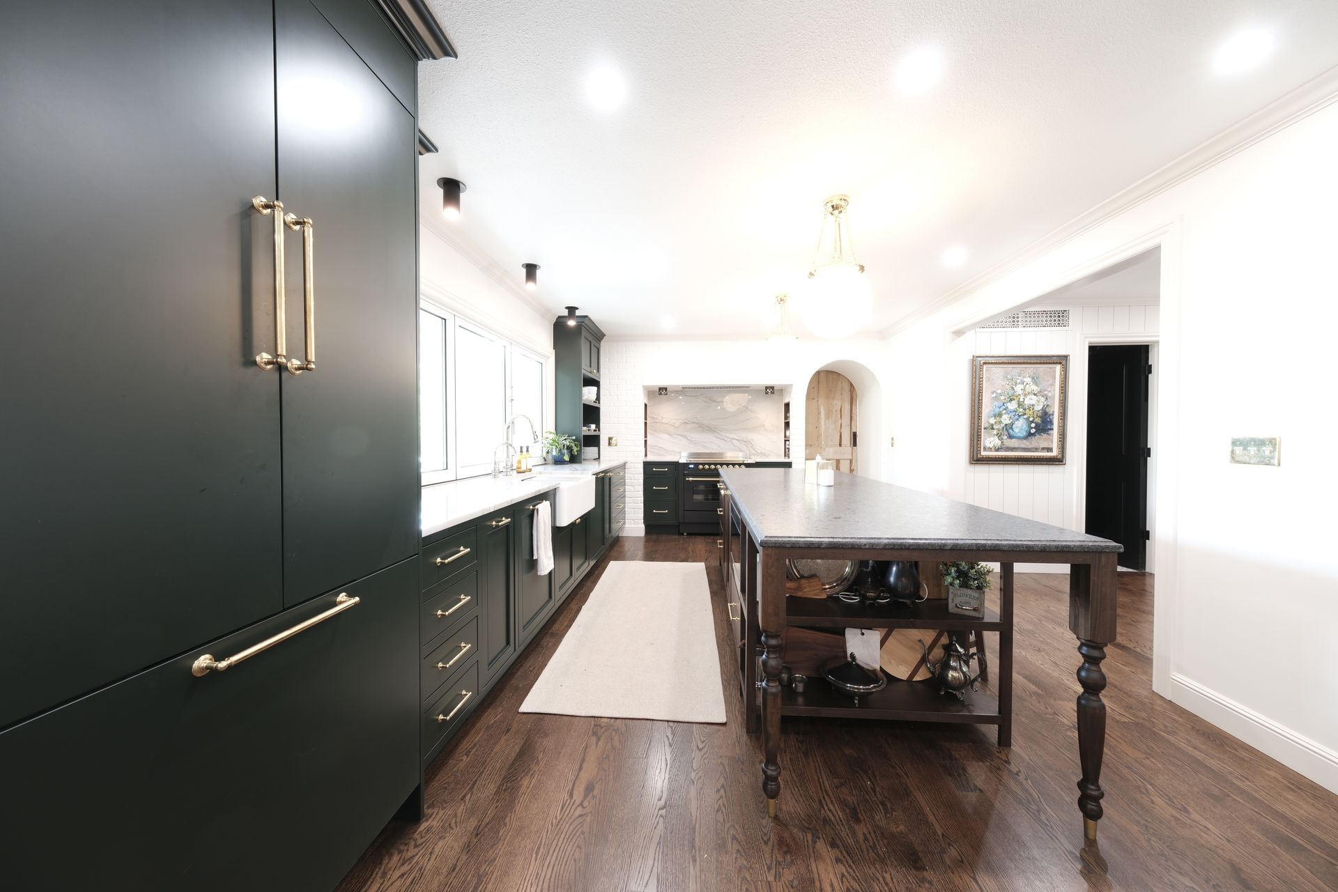 Modern kitchen and dining area with dark cabinets, wood table, and bright white walls.