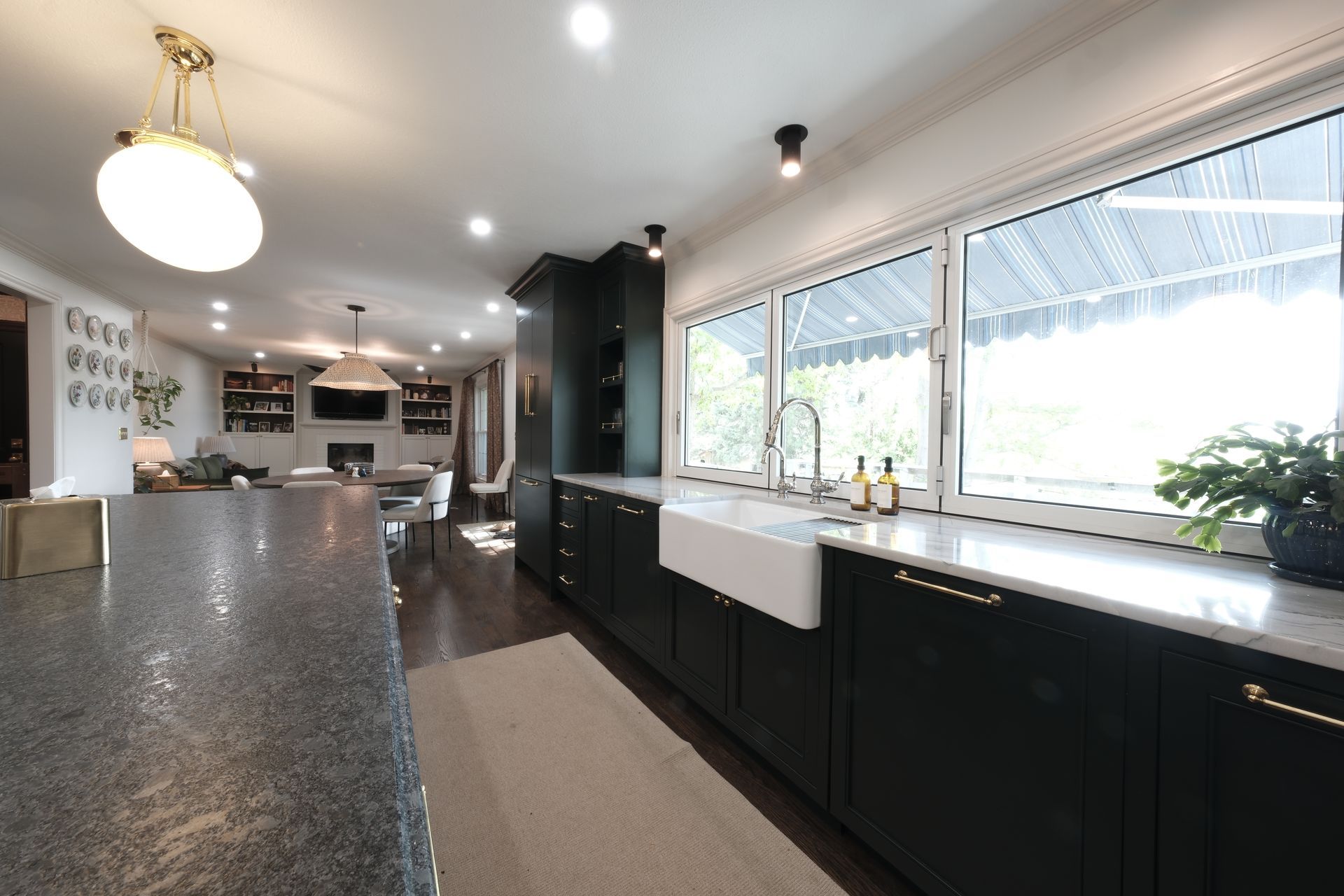 Modern kitchen with black cabinets, large windows, island, and white countertops