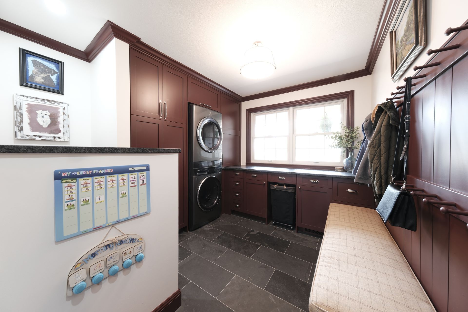 A laundry room with two washers and dryers and wooden cabinets.