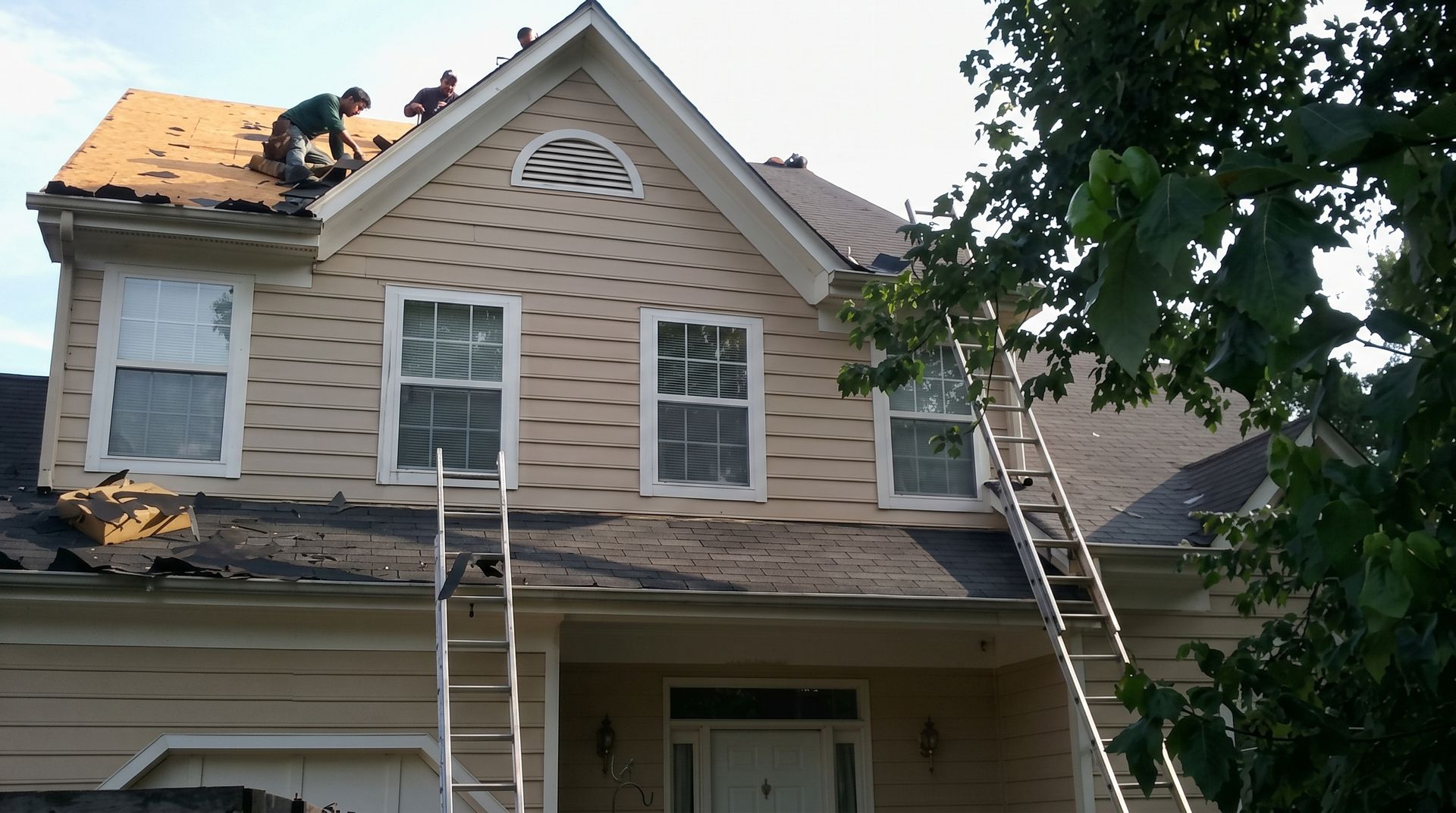 Modern house roof with gray metal panels and a wooden gable against a cloudy sky