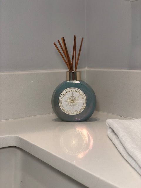 Blue aroma diffuser with reeds on a white countertop.