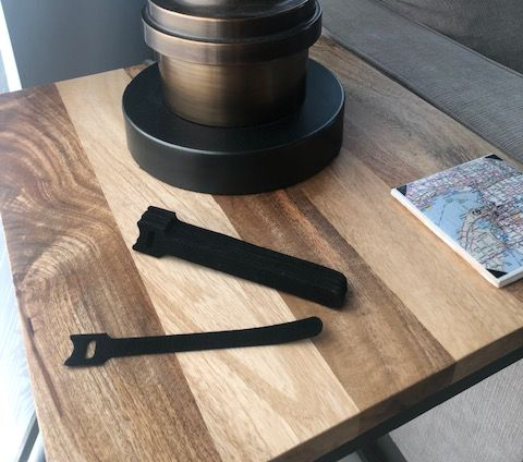 Black cable ties on a wood table with a lamp and notebook.