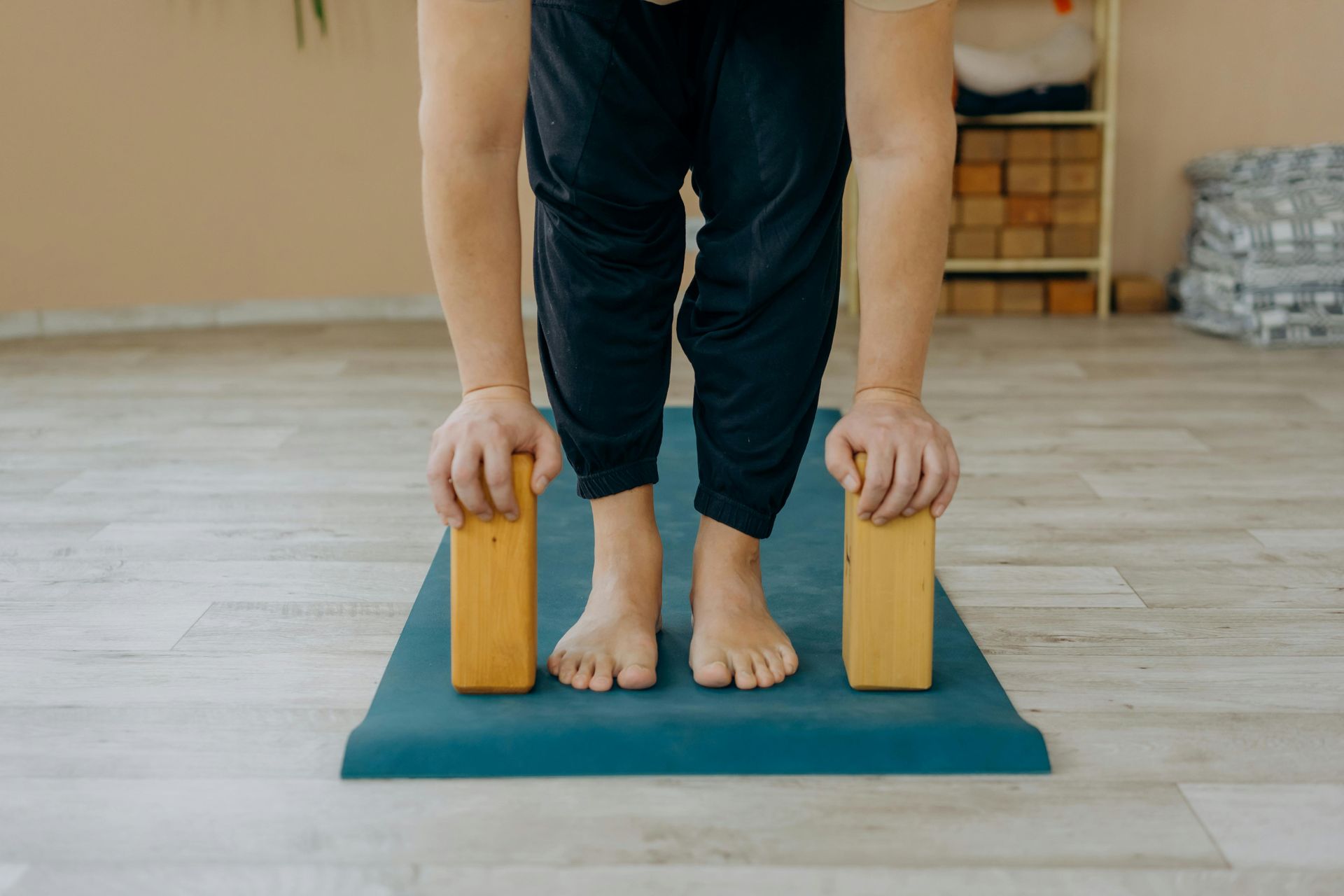 Person in yoga pose, hands on blocks, feet on a mat indoors.