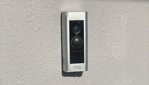 Ring video doorbell mounted on a gray stucco wall.