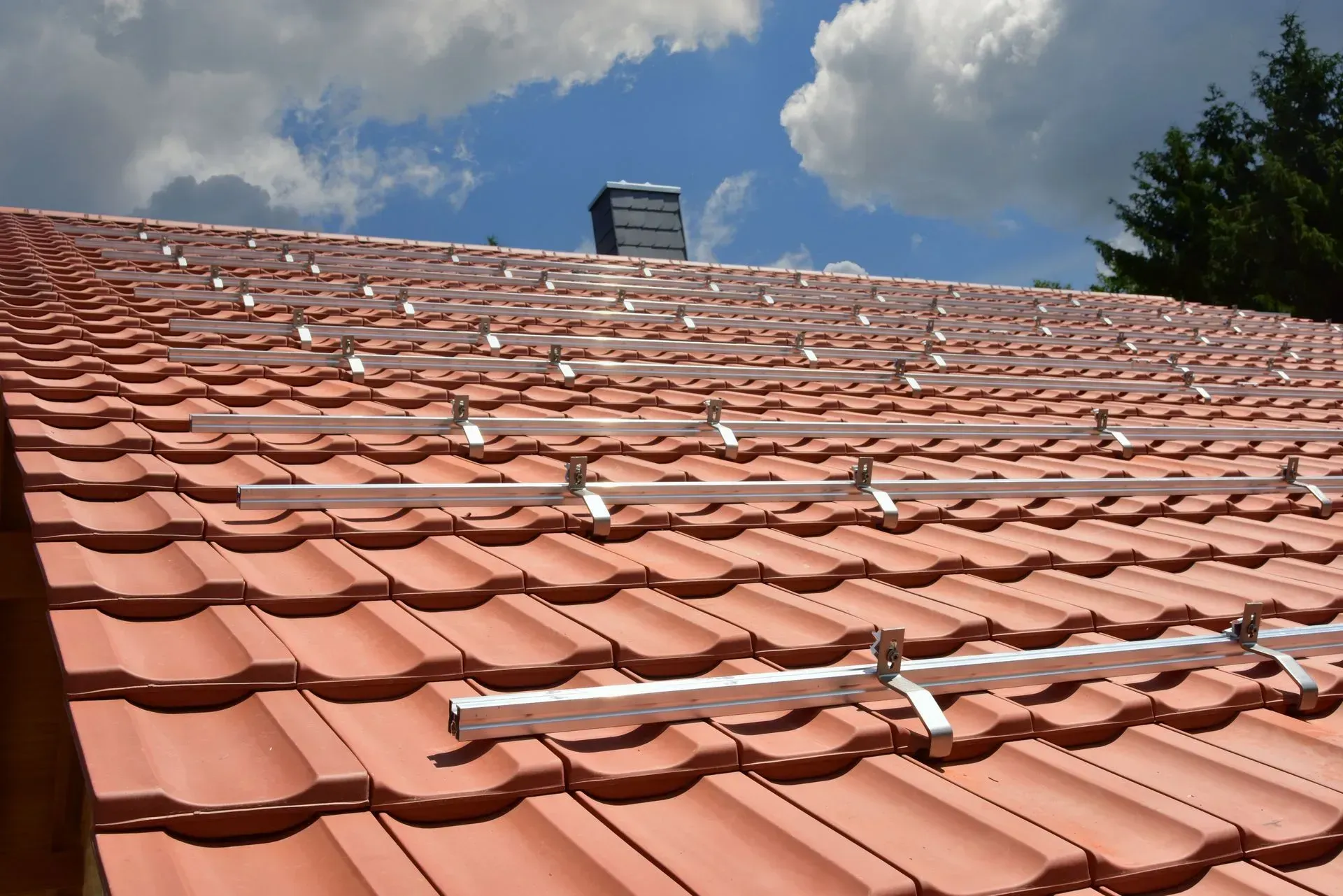 Terrakotta-Ziegeldach mit Dachkonsolen unter einem teilweise bewölkten Himmel