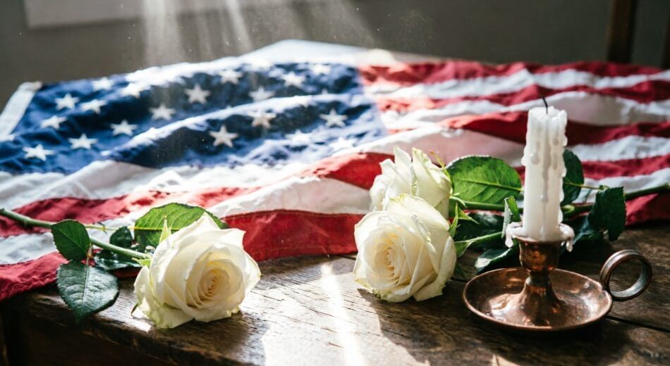 American flag with white roses and candle arranged for a memorial service in Willowick, OH
