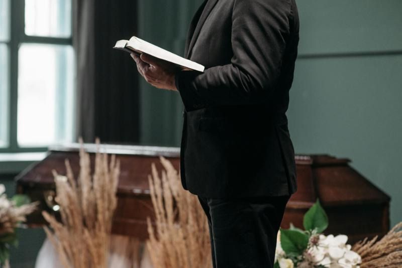 Funeral officiant holding a book, leading a respectful memorial service in a calm and dignified setting.

