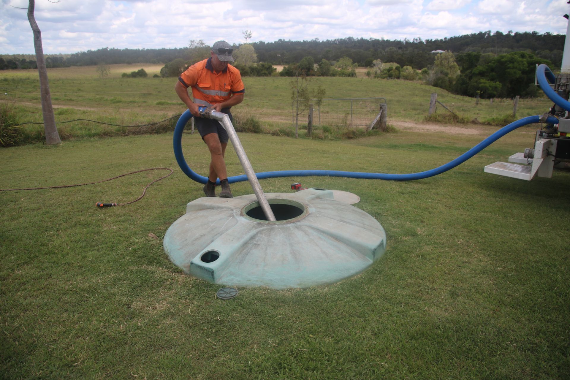 A manhole cover with a hose and gloves coming out of it.