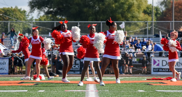 Red, white, and blue pom-poms held high by cheerleaders during a performance.