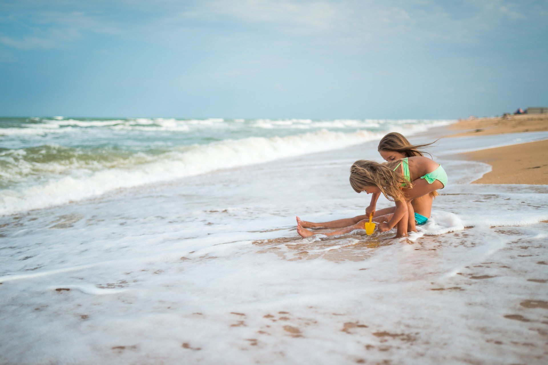 Zwei kleine Mädchen spielen im Wasser am Strand.