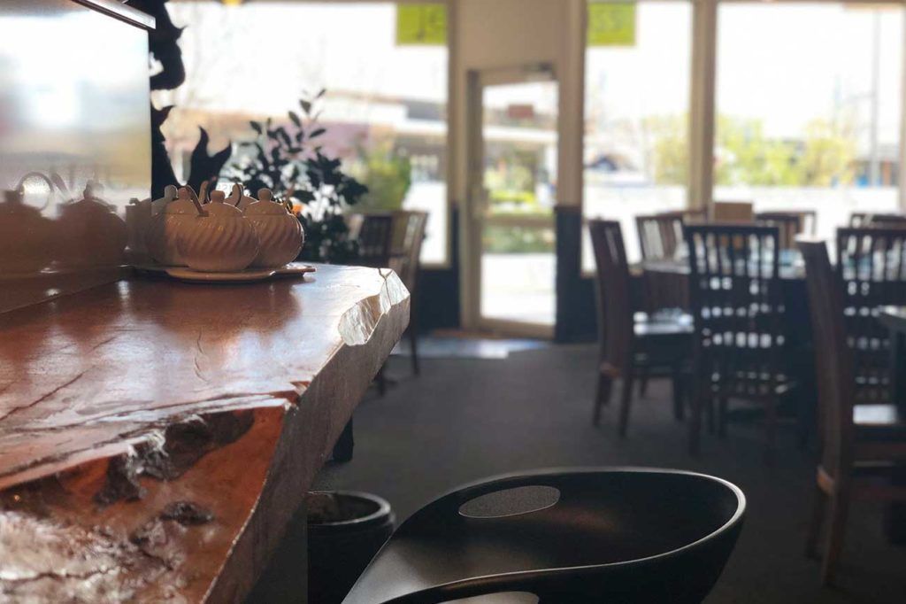 A restaurant with tables and chairs and a wooden counter