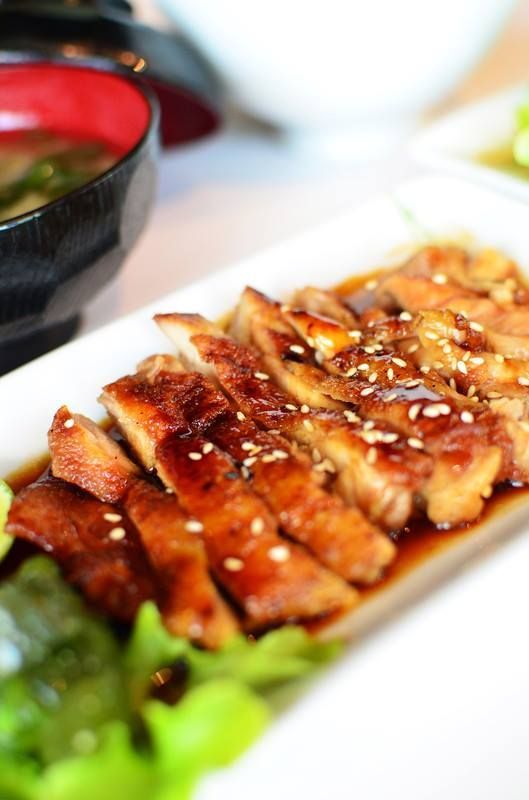 A close up of a plate of food with a bowl of soup in the background