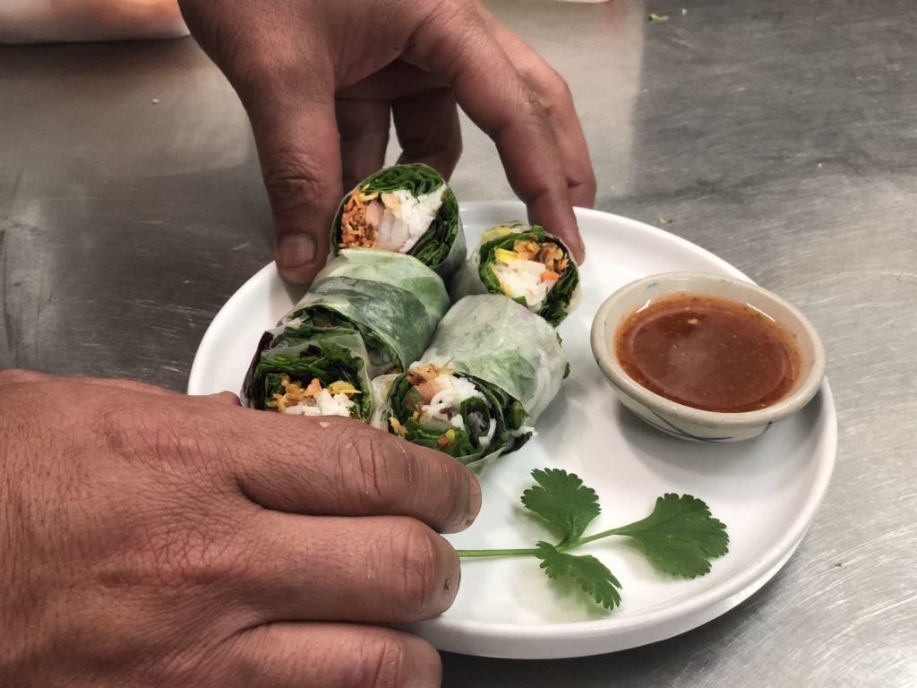 A person is holding a plate of food with a dipping sauce.